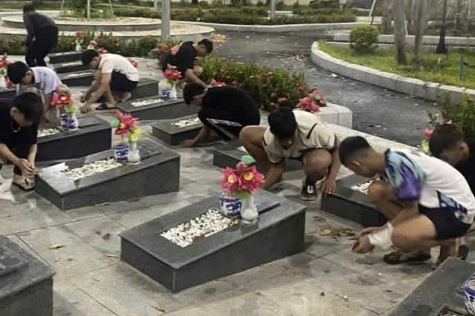 Nhóm thiếu niên quét lá, nhổ cỏ, vệ sinh khuôn viên nghĩa trang liệt sĩ. Ảnh: Công an xã Phú Giáo